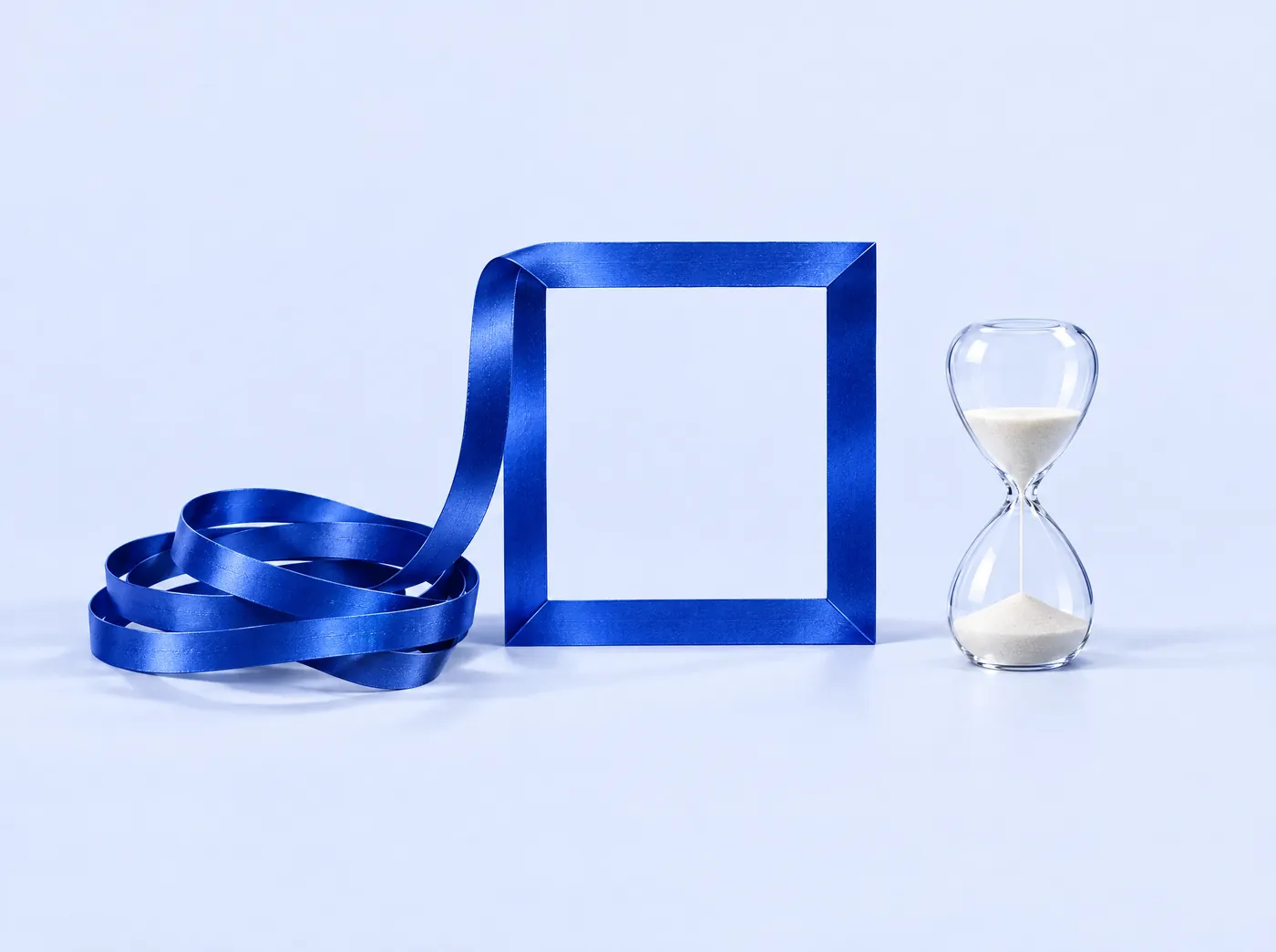 A cobalt ribbon folded into a neat square frame beside an hourglass.